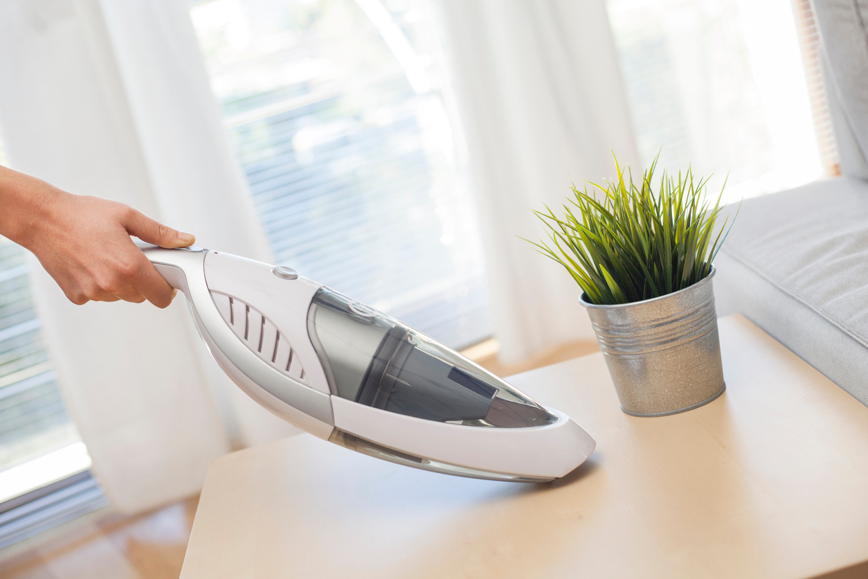 Una persona usa el aspirador de mano para limpiar los restos de la mesa.