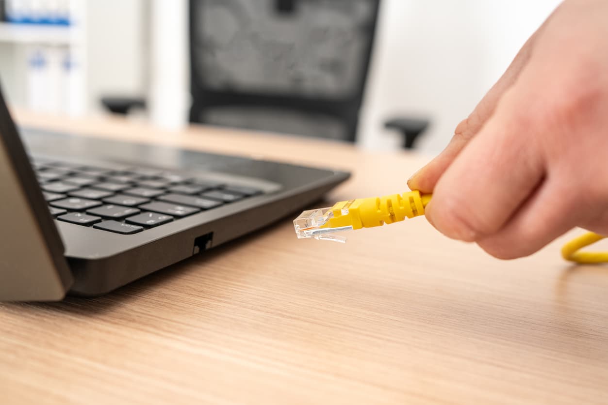 Una persona conectando el cable ethernet al portátil.