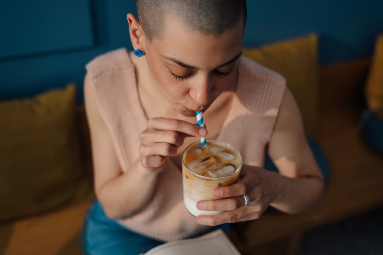 Una chica toma café con pajita en un bar.
