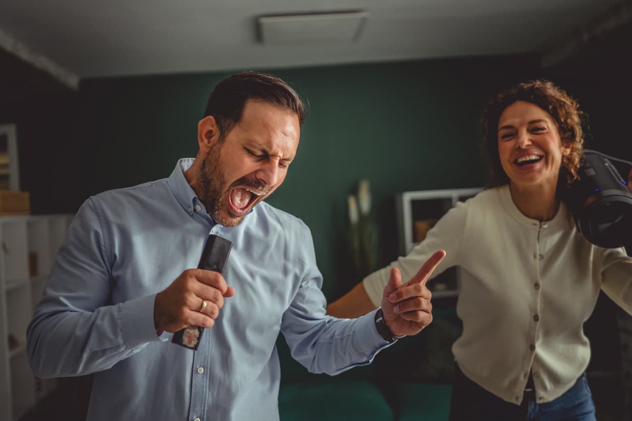 Dos adultos cantan al son de la música que sale de un altavoz portátil.