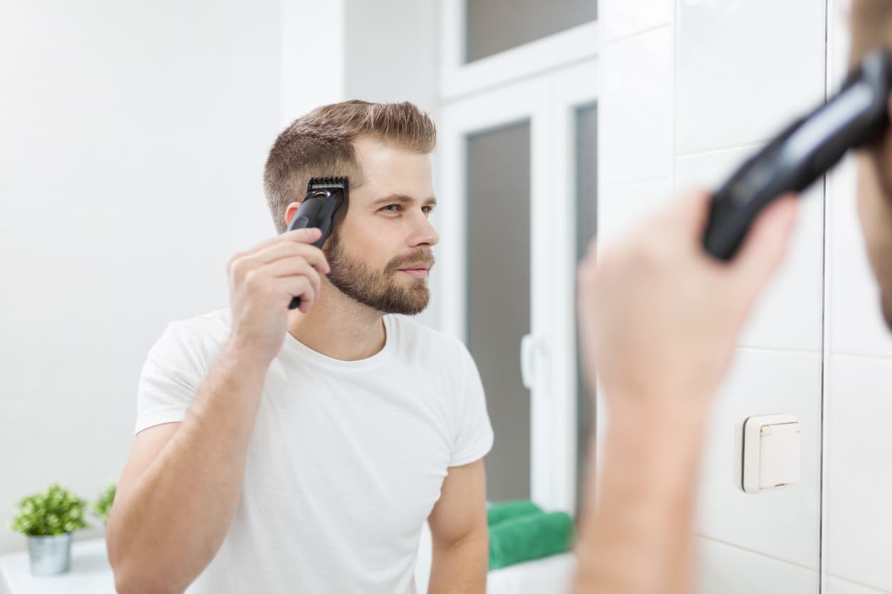 Un hombre se retoca las patillas con el cortapelo.
