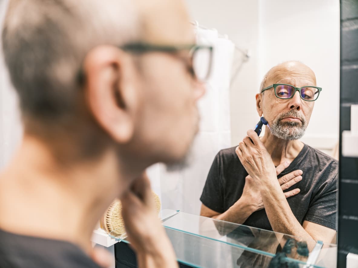 Un hombre se afeita en el baño.
