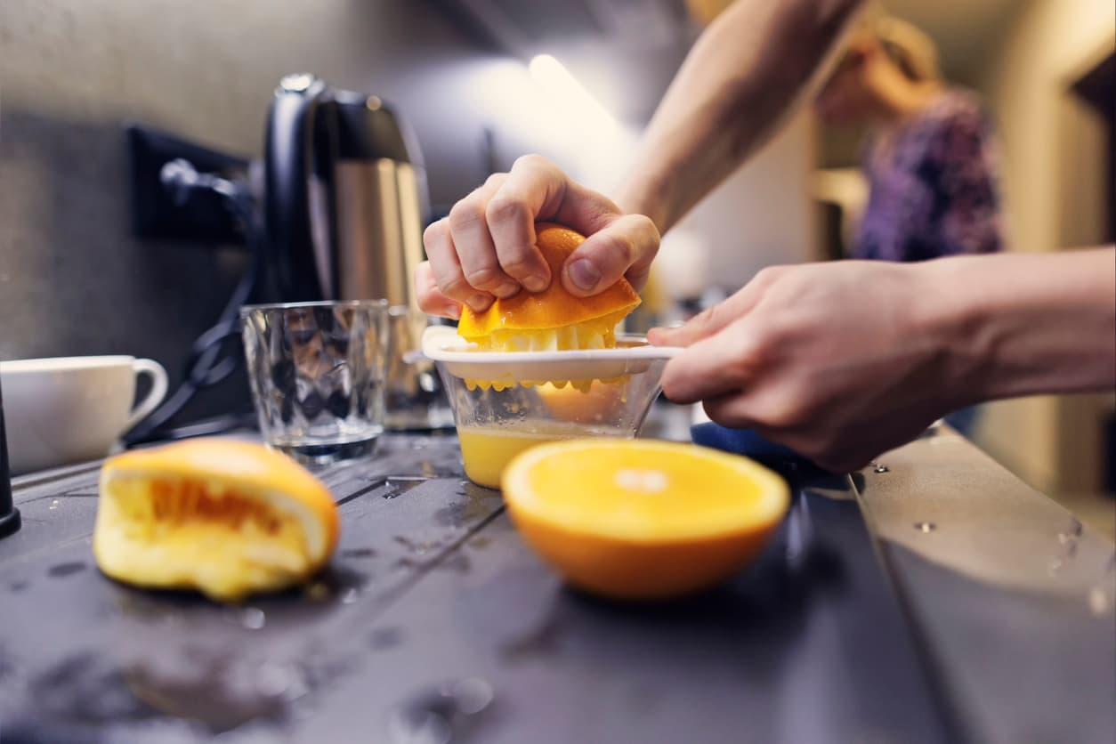 Una persona exprimiendo las naranjas con la mano.