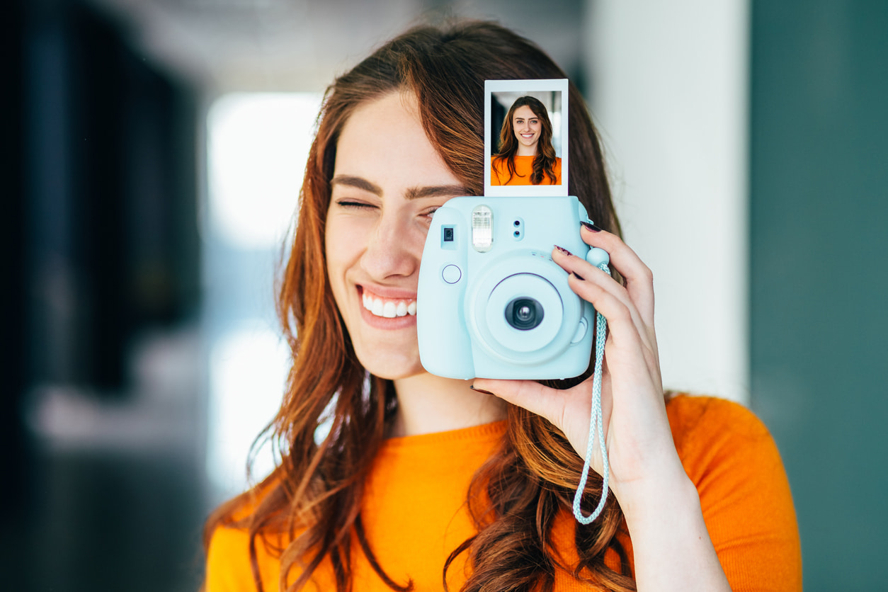 Una mujer muestra un retrato sacado con su cámara instantánea.