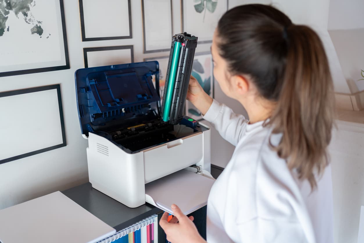 Una mujer cambia el toner de la impresora.