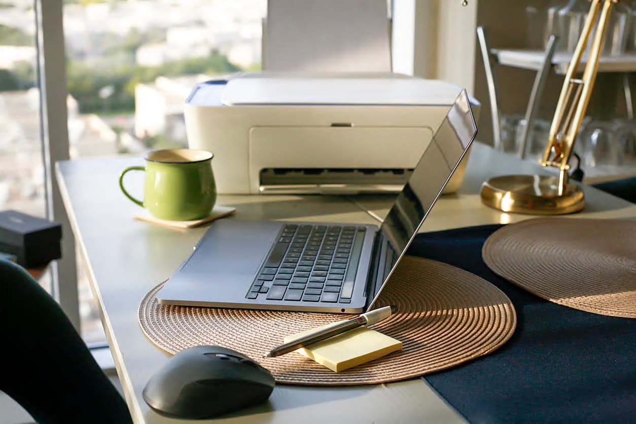 La mesa de teletrabajo de una casa incluye impresora.