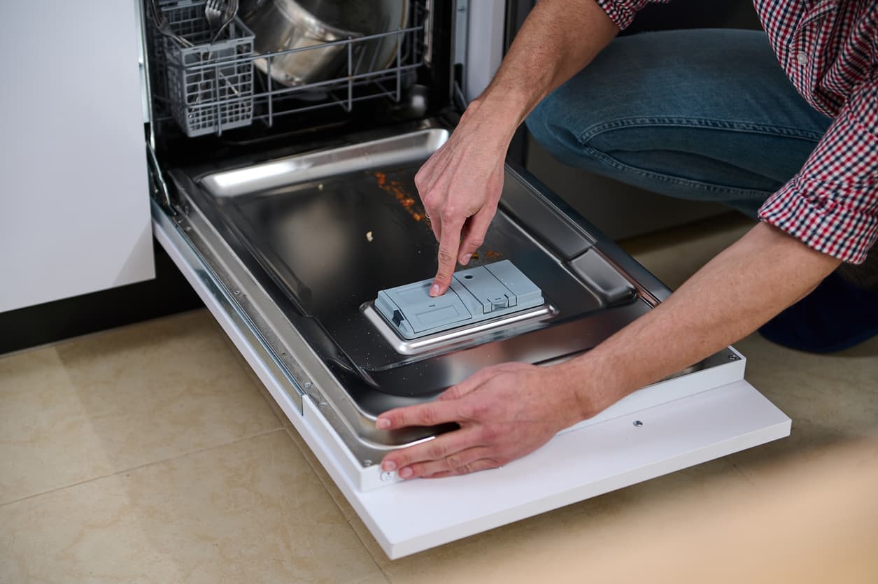Un hombre introduce la pastilla de lavavajillas en la tapa.