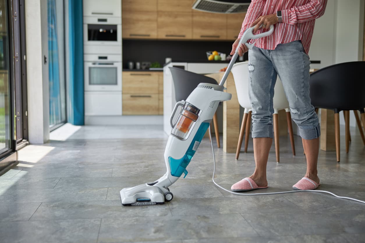 Una mujer limpia el suelo de su casa con una limpiadora multisuperficie.