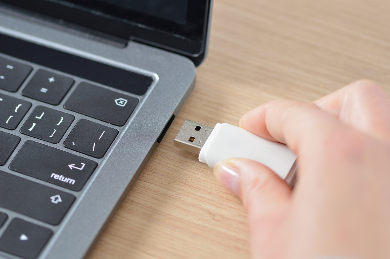 Una persona introduce su memoria externa de USB en la rendija de su portátil.