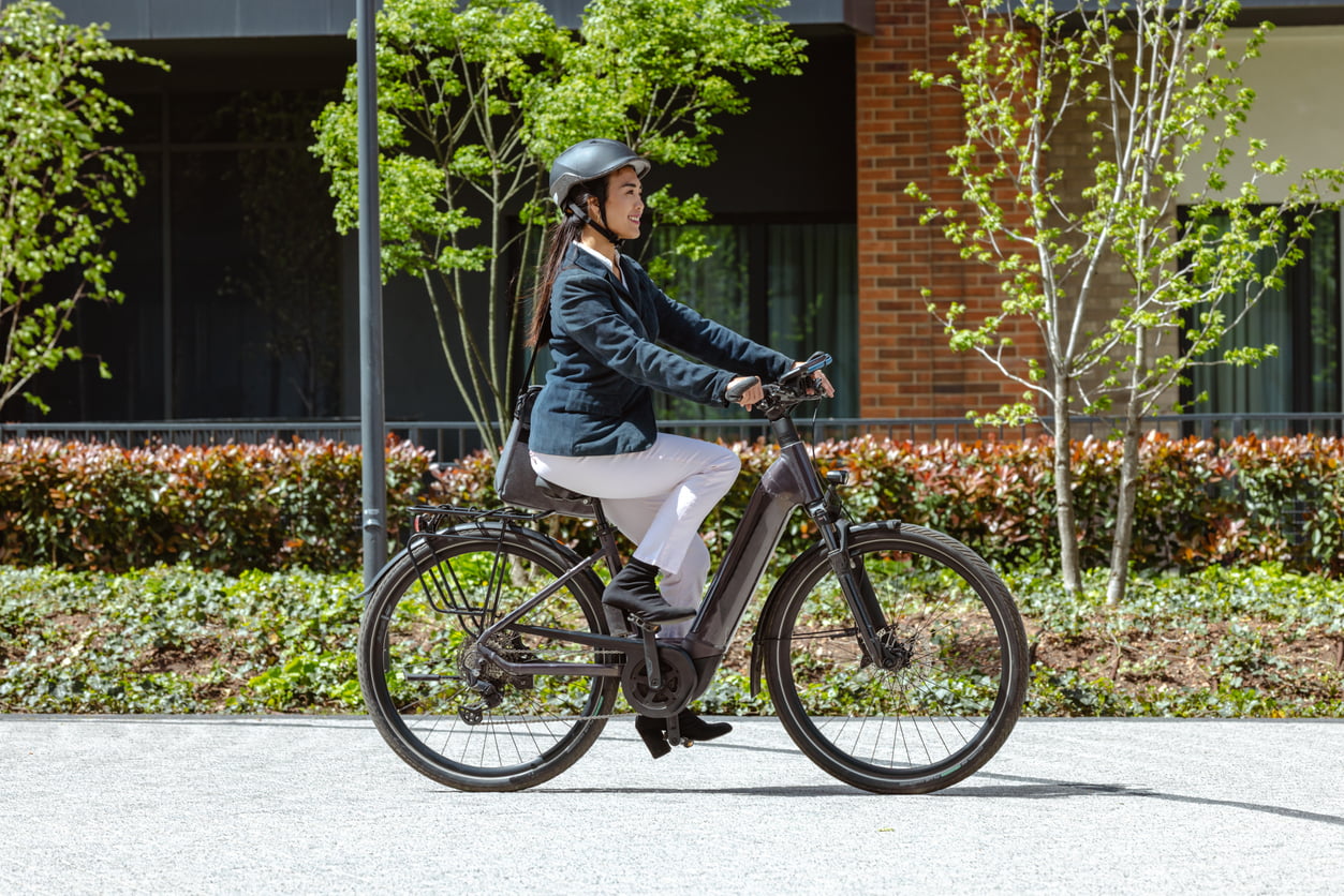 Una mujer feliz pasea por la ciudad con su bici eléctrica.