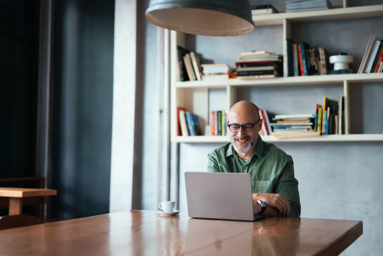 Un hombre escribe en su portátil i9 sentado en la biblioteca de su casa.