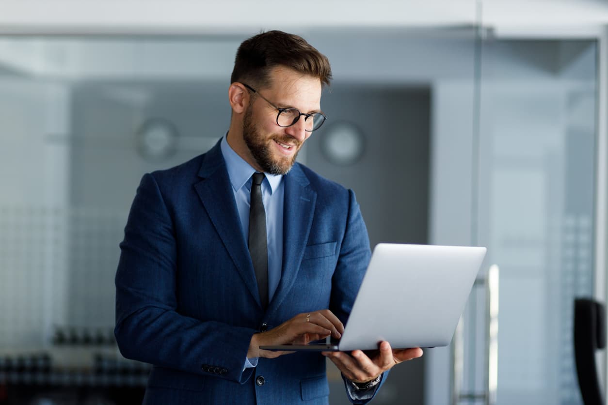 Un hombre de pie consulta en la oficina información en su portátil i9.