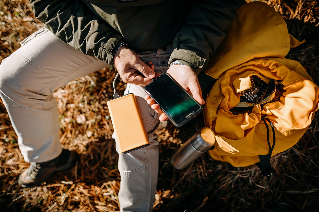 Un hombre utiliza una powerbank para cargar su móvil en el bosque.