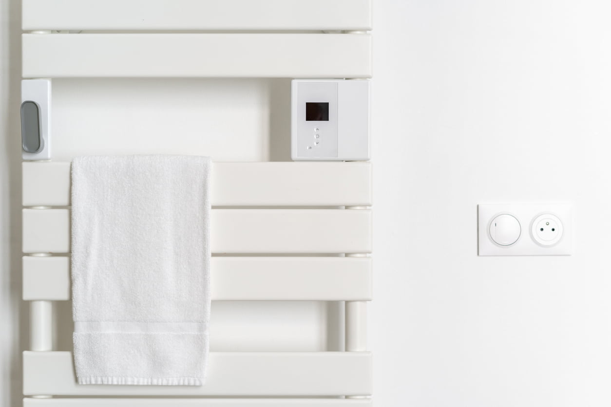 Un radiador blanco sujeta y seca las toallas de baño.