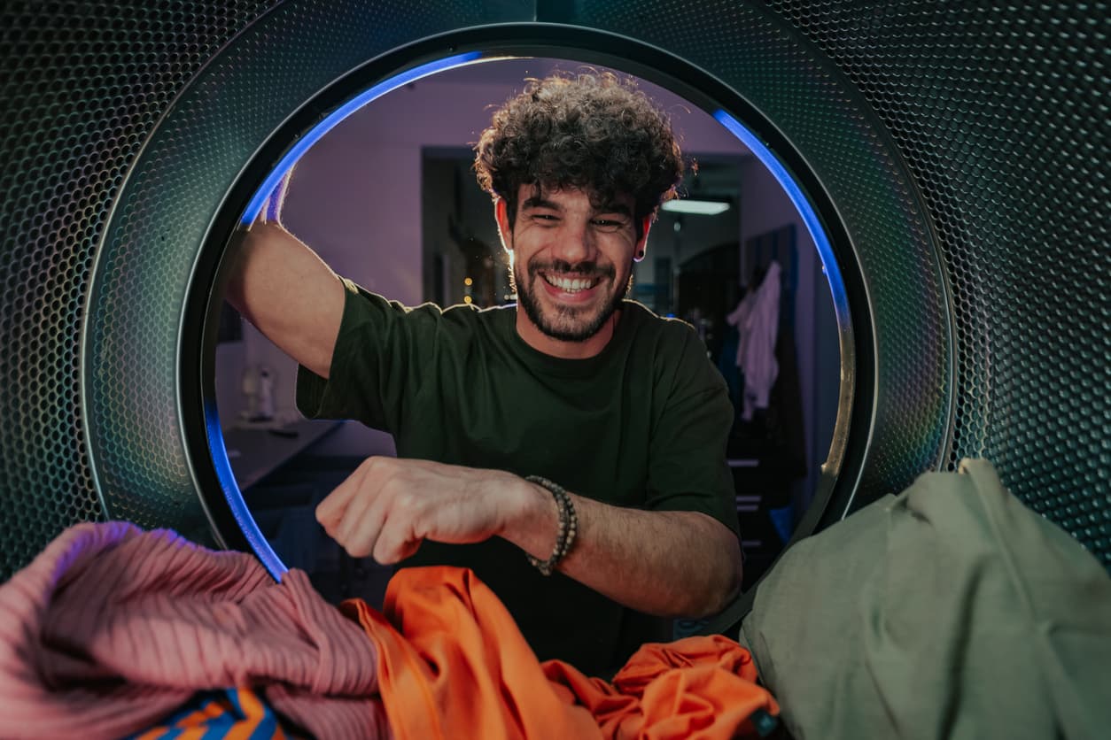 Un hombre saca la ropa en la lavadora.