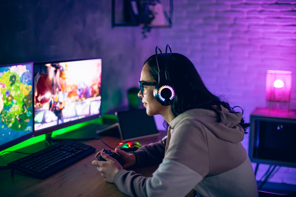 Una mujer juega con un mando en el set-up gaming de su cuarto.