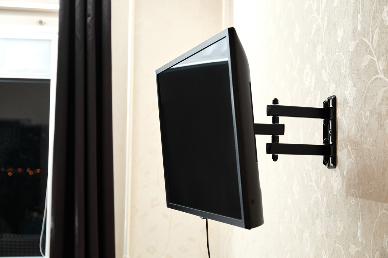 Este televisor esta colgado en la pared de un dormitorio con un soporte.