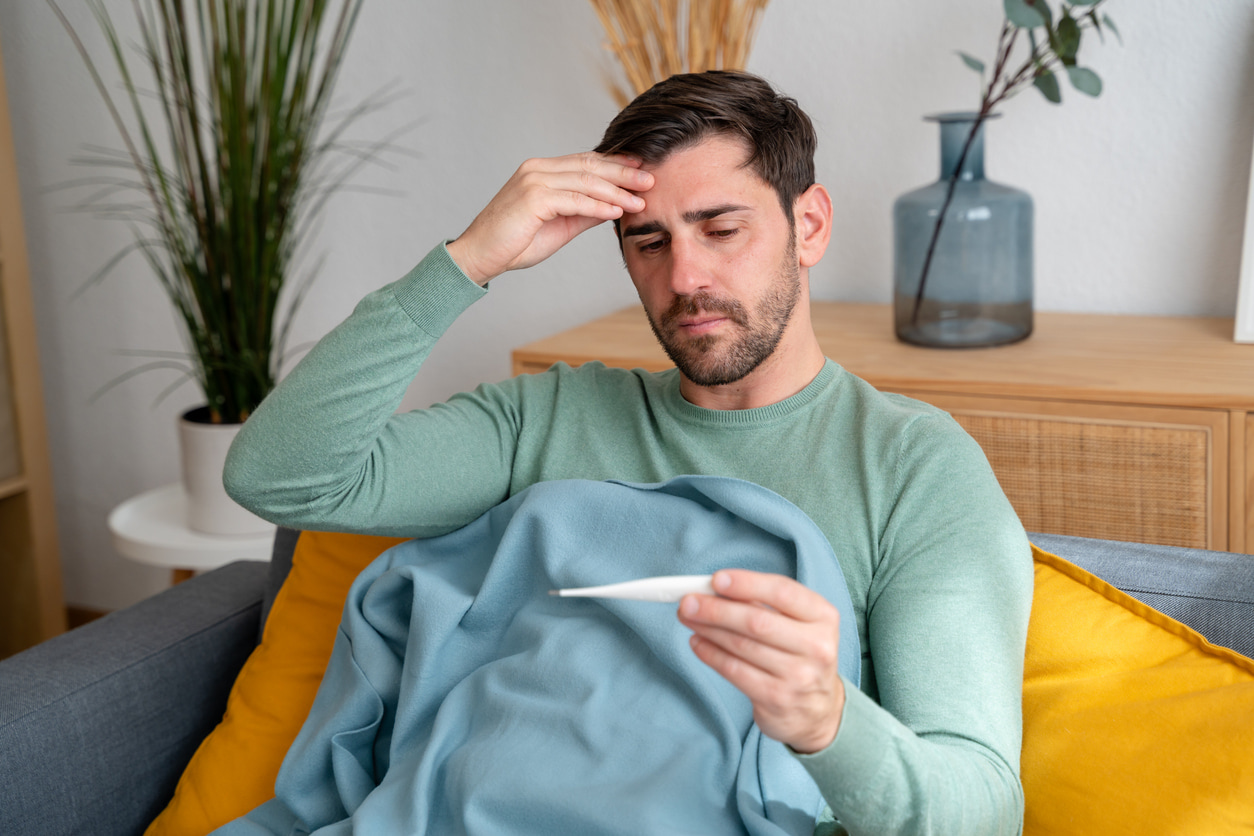 Un hombre revisa la emtperatura de su cuerpo en el termómetro.