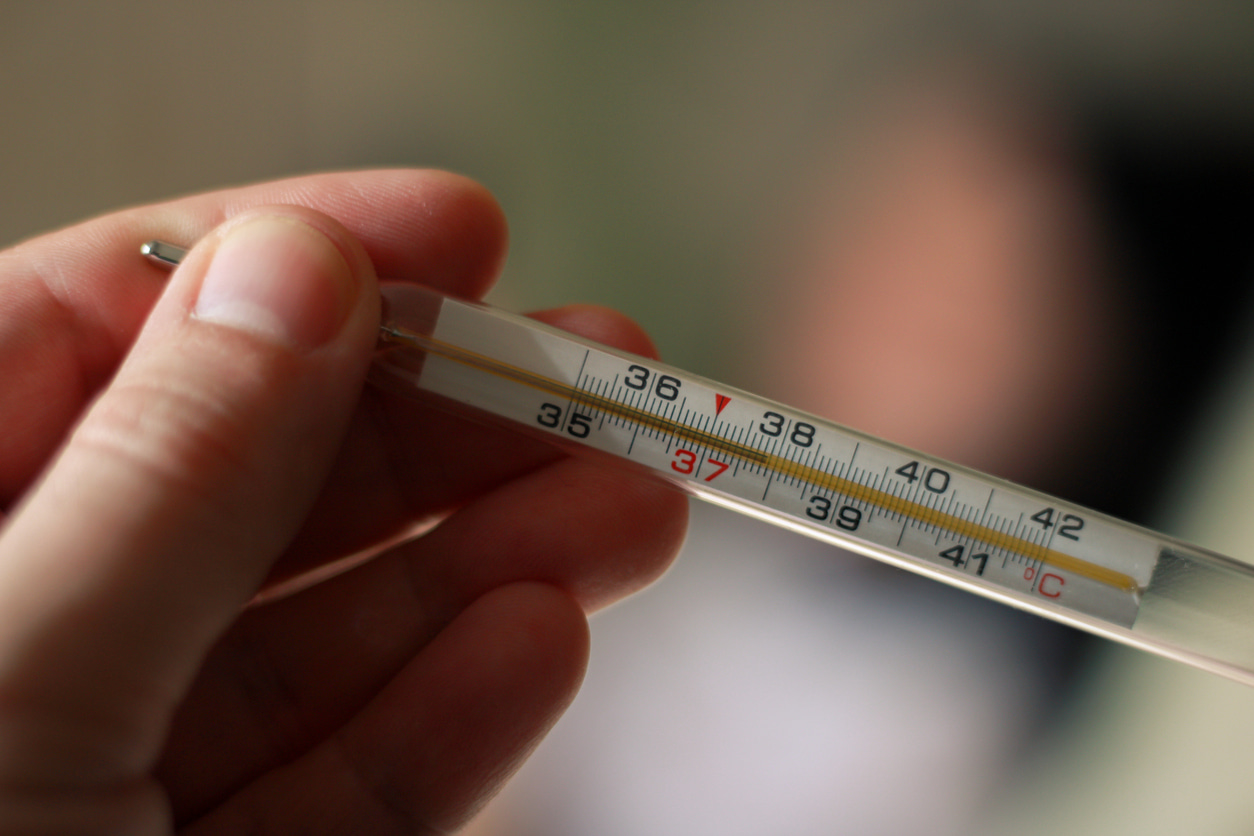 Un termómetro corporal sostenido por una mano indica 38º.